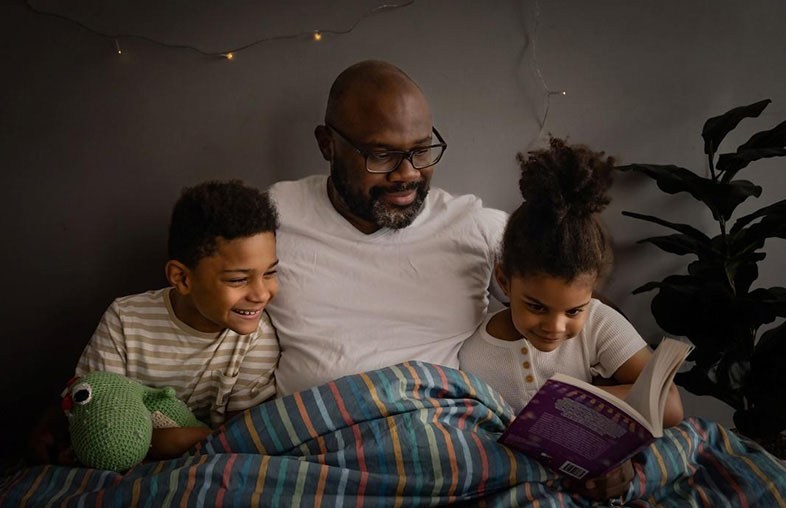 Dad reading with his two kids in bed